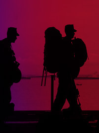The silhouettes of men in military fatigues carrying supplies.